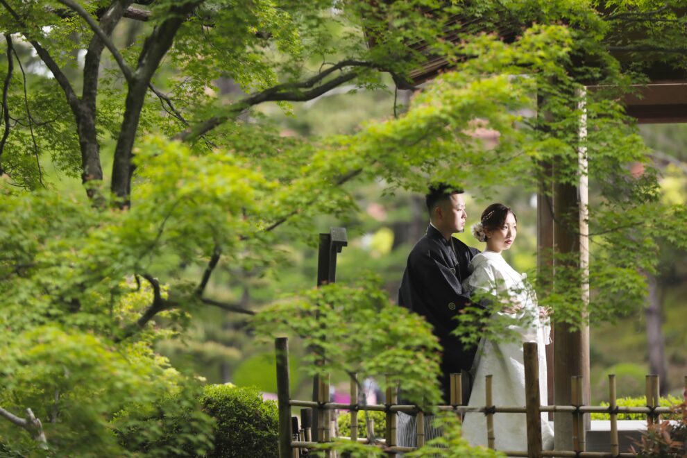 庭園で寄り添う白無垢と紋付袴のフォトウェディング・緑に包まれた上品な和装ショット