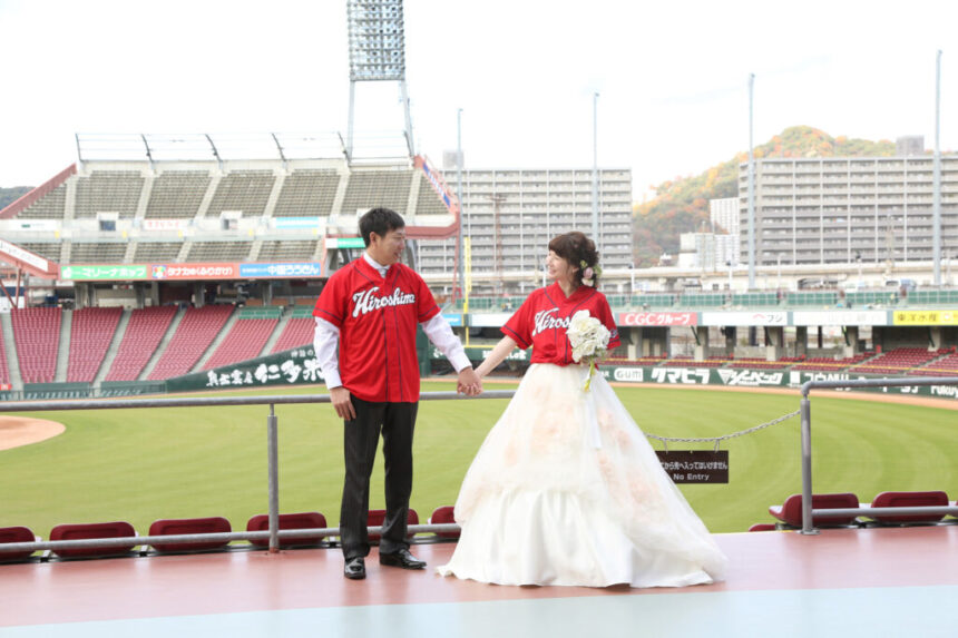 マツダスタジアムでカープのユニフォームを着た新郎新婦のフォトウェディング・スポーツと記念写真を組み合わせた特別な一枚