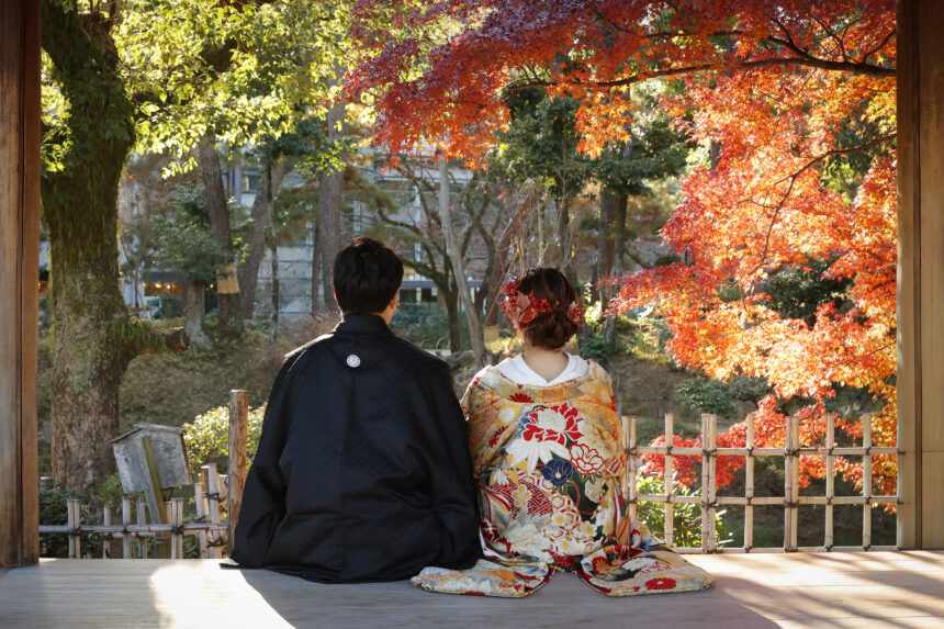 縁側に並んで座る新郎新婦の和装ロケーションフォト・紅葉の庭園を眺める穏やかな秋のひととき