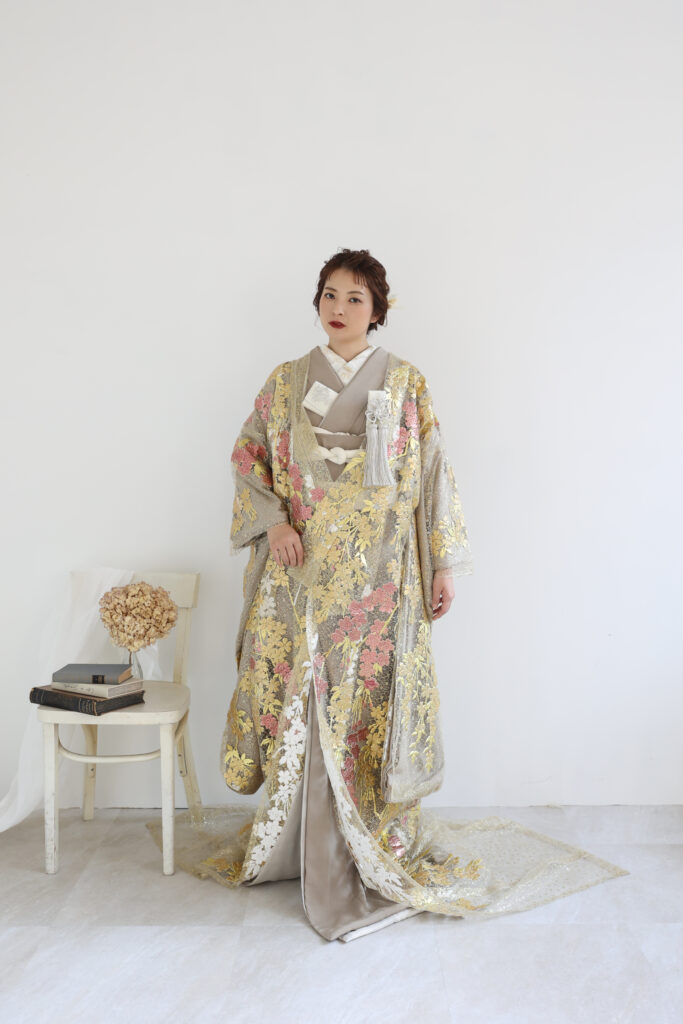 白い背景の前で華やかな色打掛をまとった女性のフォトウェディング・金彩と花柄が美しく映える上品な和装ショット